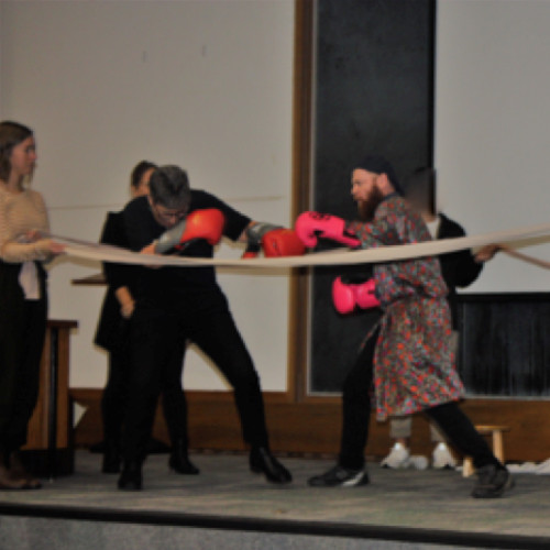 Actors onstage in mock boxing ring as part of Alone in the Ring